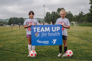 Two chi8ldren holding a Team Up for Health sign